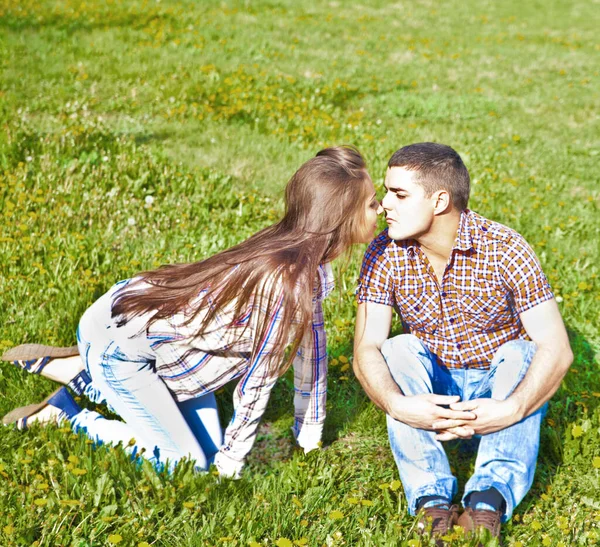 幸せな若いですヒスパニックカップル座っていると公園で緑の芝生の上でキス — ストック写真