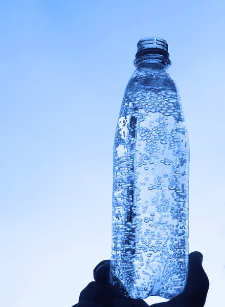 在蓝天的背景下 男性的手将新鲜清洁的饮用水放在瓶子里 空复制空间 — 图库照片