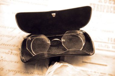 Siyah deri bir çantada beyaz arka planda izole edilmiş eski, antika gözlükler.