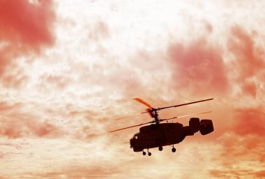 Yeşil çimlerin üzerinde uçan Rus askeri helikopterinin silueti. bulutlu gökyüzü.
