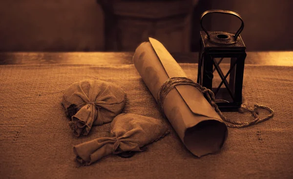 Ancient Paper Scroll , two sacks with Wax and vintage latern standing on table  with tablecloth