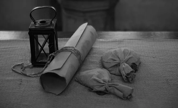 Ancient Paper Scroll , two sacks with Wax and vintage latern standing on table  with tablecloth