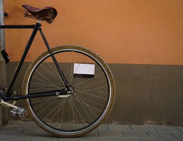 棕色和橙色墙壁背景的时髦老式黑色自行车 停在外面的自行车 水泥墙背景 空明信片在勺子之间 — 图库照片