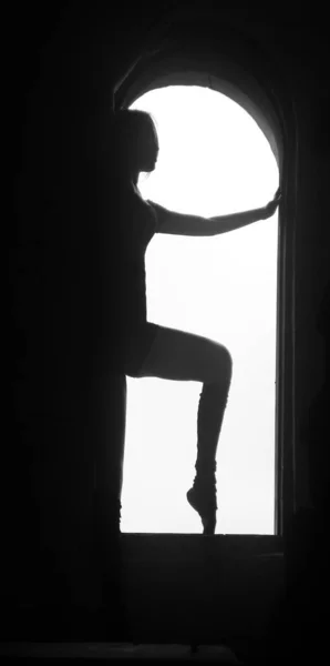 巨大な窓の上に立つ若い良い形のバレリーナのシルエット — ストック写真
