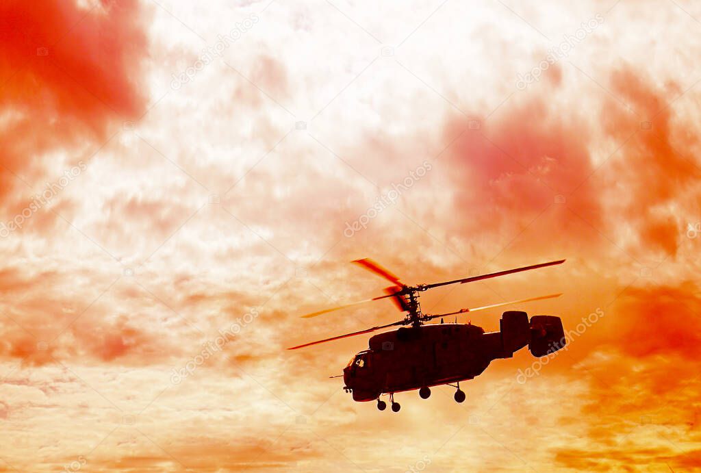 silhouette of russian military helicopter flying above green grass. cloudy sky.