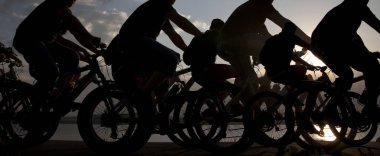 Boşluk. Gün batımında bisiklete binen sportif arkadaşlar. Bisikletçiler sahil boyunca gidiyor. Doğa arka planında spor.