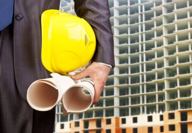 Sarı miğfer ve planları elinde tutan mühendis eli.