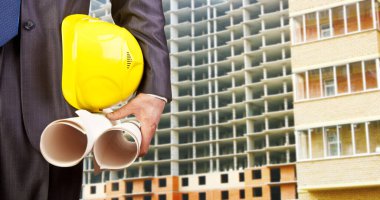 Sarı miğfer ve planları elinde tutan mühendis eli.