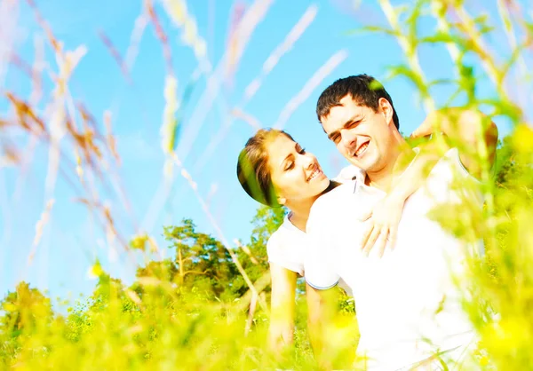 幸せな若いカップルが草の上に座って — ストック写真