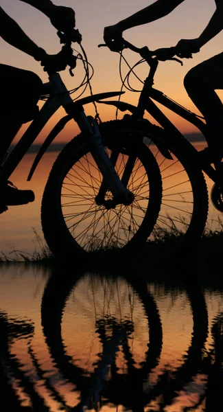 日没の自転車でスポーティ友達 海岸線沿いのカップルのシルエット — ストック写真