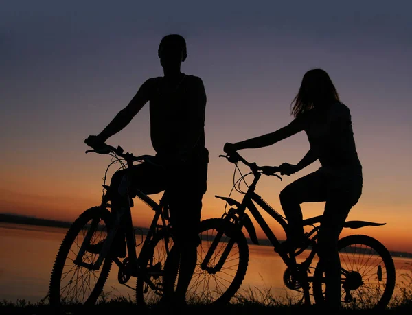 日落时骑自行车的朋友们 沿海岸线的夫妻简况 — 图库照片
