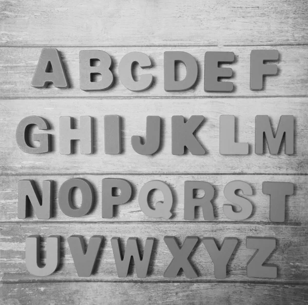 Wooden letters of English alphabet on  board  background, top view