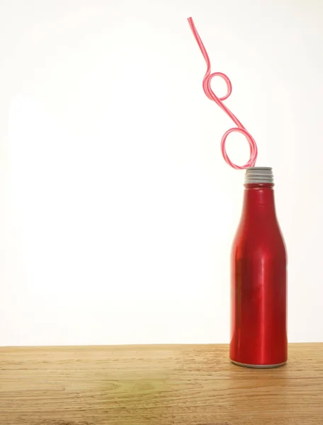 红色铝瓶 木制桌子上有稻草 白色背景隔离 红色可乐金属瓶 装有管子 — 图库照片