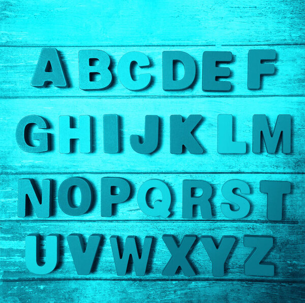 Wooden letters of English alphabet on  board  background, top view