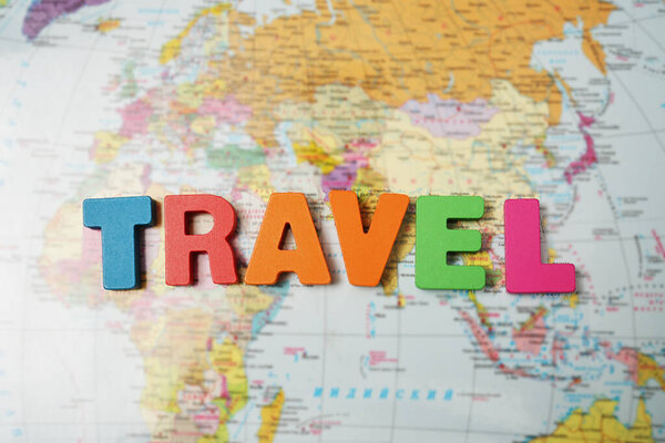 Word travel made from letters. world map background. top view.