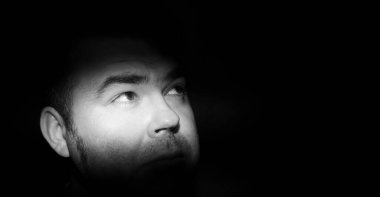 Korku için kahverengi gözlü bir adamın portresi. Yüzünde ve gözlerinde dar bir ışık şeridi var. Alacakaranlıkta kabus 