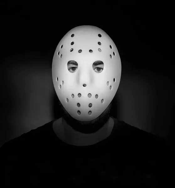 Scary hockey white mask  on young man isolated on black background. nightmare in dark. night scene