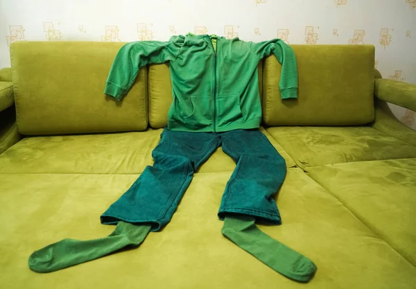 リビングルームでソファの上の男性緑の服 ズボン パーカー — ストック写真