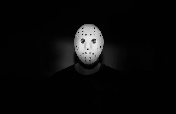 Scary hockey white mask  on young man isolated on black background. nightmare in dark. night scene