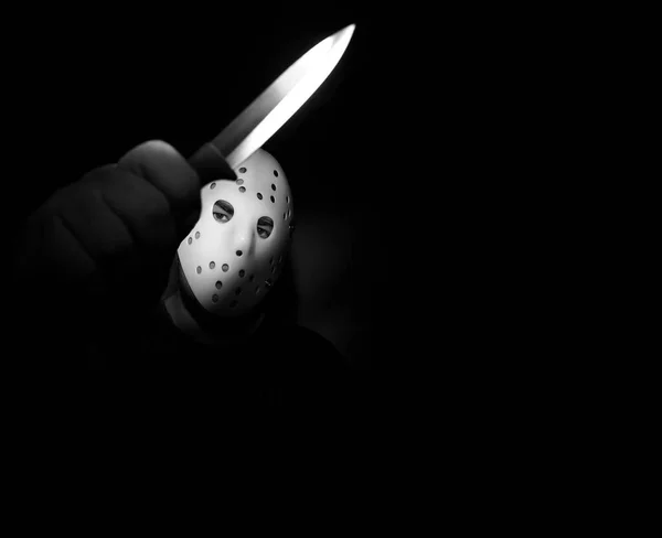 man wear white hockey mask with one  knife  on a black background