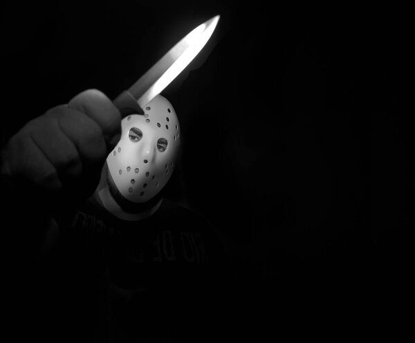 man wear white hockey mask with one  knife  on a black background