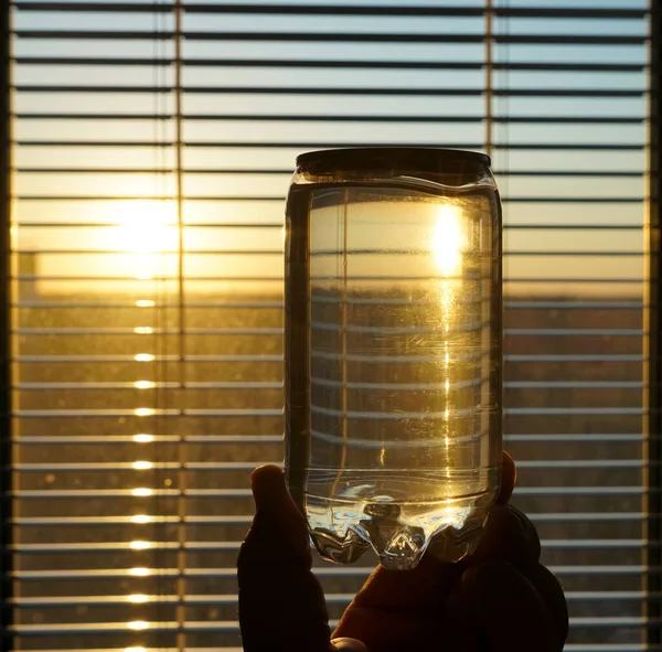 Hand Halten Transparente Plastikwasserkanister Morgenlicht Auf Dem Hintergrund Eines Fensters — Stockfoto