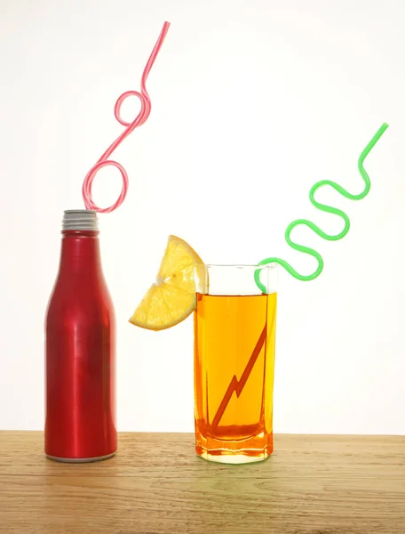 白い背景に隔離された木製のテーブルの上にわらとアルミボトルの新鮮なオレンジジュースのスライスと飲料 チューブ付きの赤いコーラ金属ボトル — ストック写真