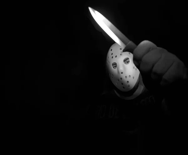 man wear white hockey mask with one  knife  on a black background