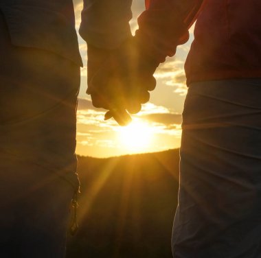 Birbirine aşık çiftler el ele tutuşuyor. Mutlu Romantik Genç Çift Dağda Güzel Günbatımının keyfini çıkarın. Neşeli çift gün batımında el ele tutuşuyor. Seyahat Tatili Yaşam Tarzı Konsepti. arka görünüm