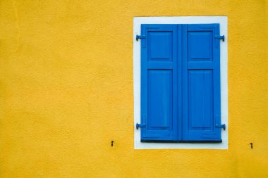 Yeni modern mavi kepenkler, konutun sarı duvarı.