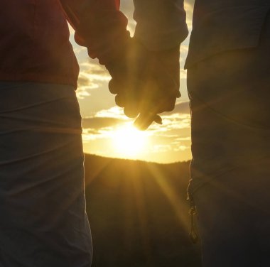 Birbirine aşık çiftler el ele tutuşuyor. Mutlu Romantik Genç Çift Dağda Güzel Günbatımının keyfini çıkarın. Neşeli çift gün batımında el ele tutuşuyor. Seyahat Tatili Yaşam Tarzı Konsepti. arka görünüm