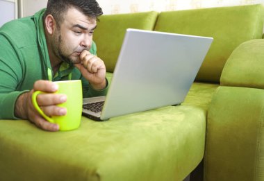 Serbest çalışan adam, dizüstü bilgisayarını kullanarak yalan söylemeyi ve kanepede dinlenmeyi başarıyor. Limon çayı ve dizüstü bilgisayarla çalıştıktan sonra, çalışan adam ev kavramında küçük işler yapıyor..