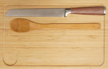 Yeni dikdörtgen tahta tabak, demir bıçak ve tahta kaşık. Ahşap masa arka planında gayri resmi masa ayarları. Ahşap masa üstünde kırsal çatal bıçak takımı