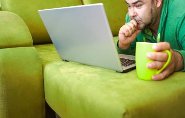 Serbest çalışan adam, dizüstü bilgisayarını kullanarak yalan söylemeyi ve kanepede dinlenmeyi başarıyor. Limon çayı ve dizüstü bilgisayarla çalıştıktan sonra, çalışan adam ev kavramında küçük işler yapıyor..