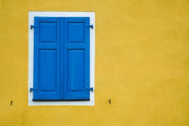 Yeni modern mavi kepenkler, konutun sarı duvarı.