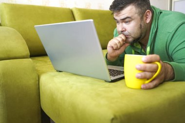 Serbest çalışan adam, dizüstü bilgisayarını kullanarak yalan söylemeyi ve kanepede dinlenmeyi başarıyor. Limon çayı ve dizüstü bilgisayarla çalıştıktan sonra, çalışan adam ev kavramında küçük işler yapıyor..