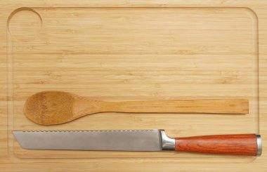 Yeni dikdörtgen tahta tabak, demir bıçak ve tahta kaşık. Ahşap masa arka planında gayri resmi masa ayarları. Ahşap masa üstünde kırsal çatal bıçak takımı