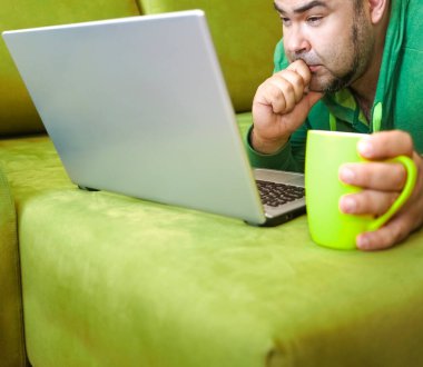 Serbest çalışan adam, dizüstü bilgisayarını kullanarak yalan söylemeyi ve kanepede dinlenmeyi başarıyor. Limon çayı ve dizüstü bilgisayarla çalıştıktan sonra, çalışan adam ev kavramında küçük işler yapıyor..