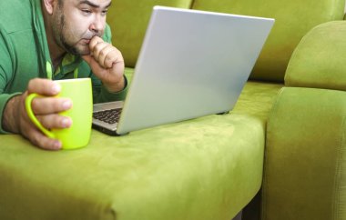 Serbest çalışan adam, dizüstü bilgisayarını kullanarak yalan söylemeyi ve kanepede dinlenmeyi başarıyor. Limon çayı ve dizüstü bilgisayarla çalıştıktan sonra, çalışan adam ev kavramında küçük işler yapıyor..