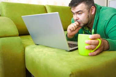 Serbest çalışan adam, dizüstü bilgisayarını kullanarak yalan söylemeyi ve kanepede dinlenmeyi başarıyor. Limon çayı ve dizüstü bilgisayarla çalıştıktan sonra, çalışan adam ev kavramında küçük işler yapıyor..