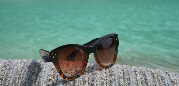 夏假的概念形象 在沙发上的太阳镜中的海滩场景 蓝色海背景的太阳镜 夏天配饰和假日旅行的概念 有选择的重点 — 图库照片