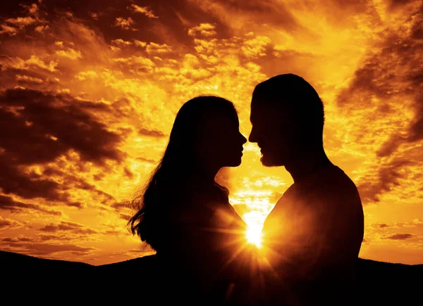 A silhouette of a close up of a woman and man. face to face. Silhouette of a loving couple hugging on a sunset background. couple in love. sunset light. romantic evening.