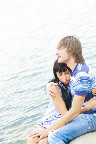 Young couple in blue jeans on blue water background. Beautiful happy couple in love lying on a beach in a white shirts are in love. Summer, holidays, vacation and happy people concept. closed eyes.