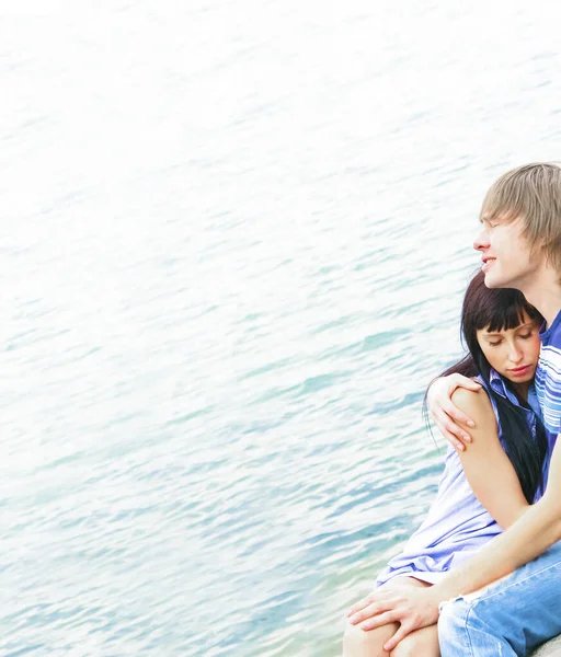 青い水の背景に青いジーンズの若いカップル 白いシャツを着たビーチに横たわる愛の美しい幸せなカップルが恋をしています 幸せな人々の概念 目を閉じて — ストック写真