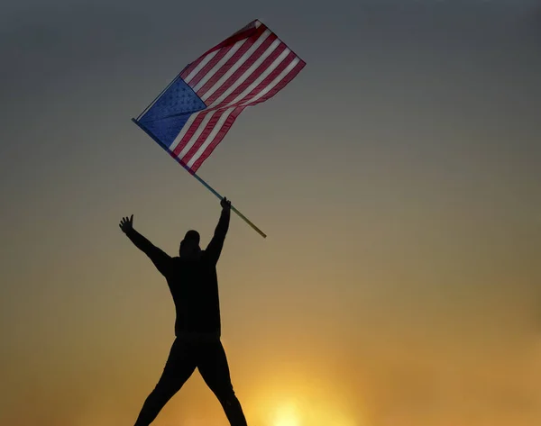 Man Springt Met Amerikaanse Vlag Een Man Silhouet Bij Zonsondergang — Stockfoto