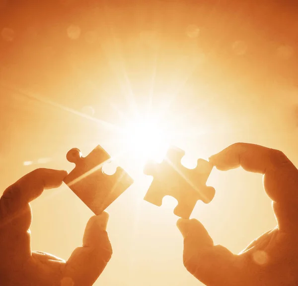 hands  with  puzzle pieces on sky background.