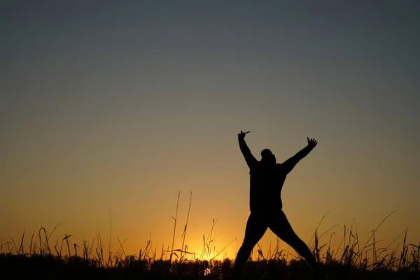 太陽光線の中に飛び込む男 夕暮れ時のシルエットの男が飛び跳ねて楽しんでる 人々のための幸福と自由の概念は屋外レジャー活動を楽しむ — ストック写真