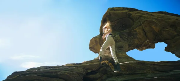 Young woman climbing on cliff of mountain.