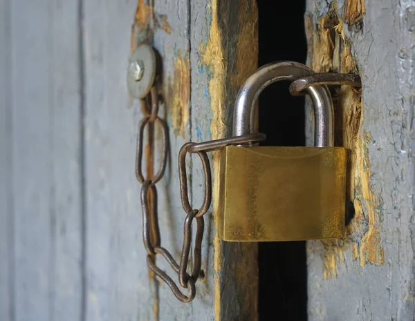 Kapıda eski demir kilit asılı. Kilitli, asma kilitli, ahşap bir kapı.