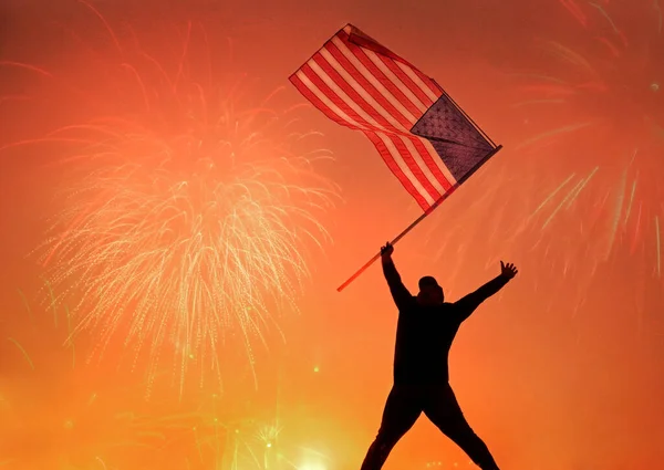 七月四日举着美国国旗跳爱国者女孩的轮廓 爱国节假日快乐的年轻人拿着美国国旗看着烟火 美国庆祝七月四日 — 图库照片